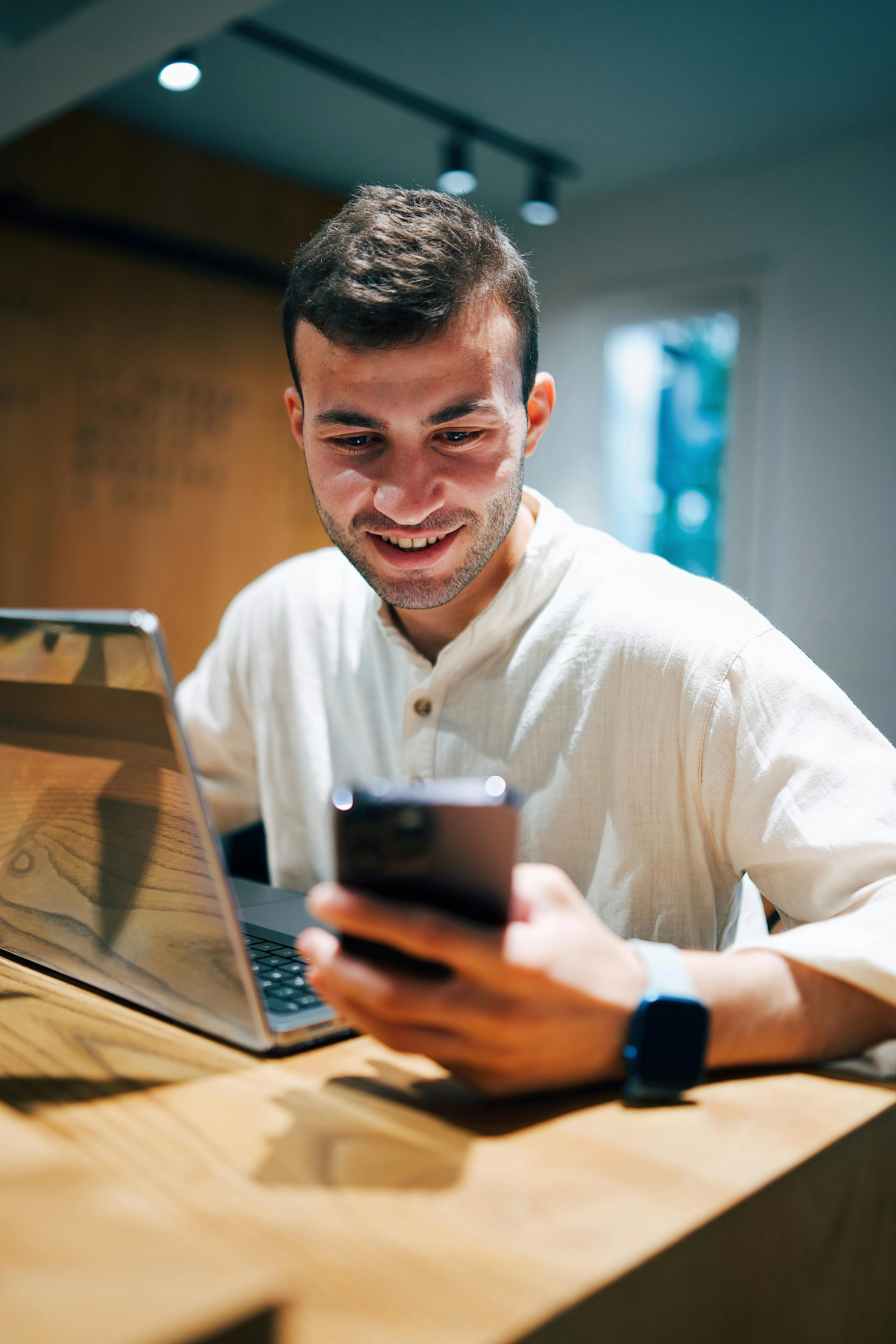 Мужчина улыбается, читая сообщение на смартфоне