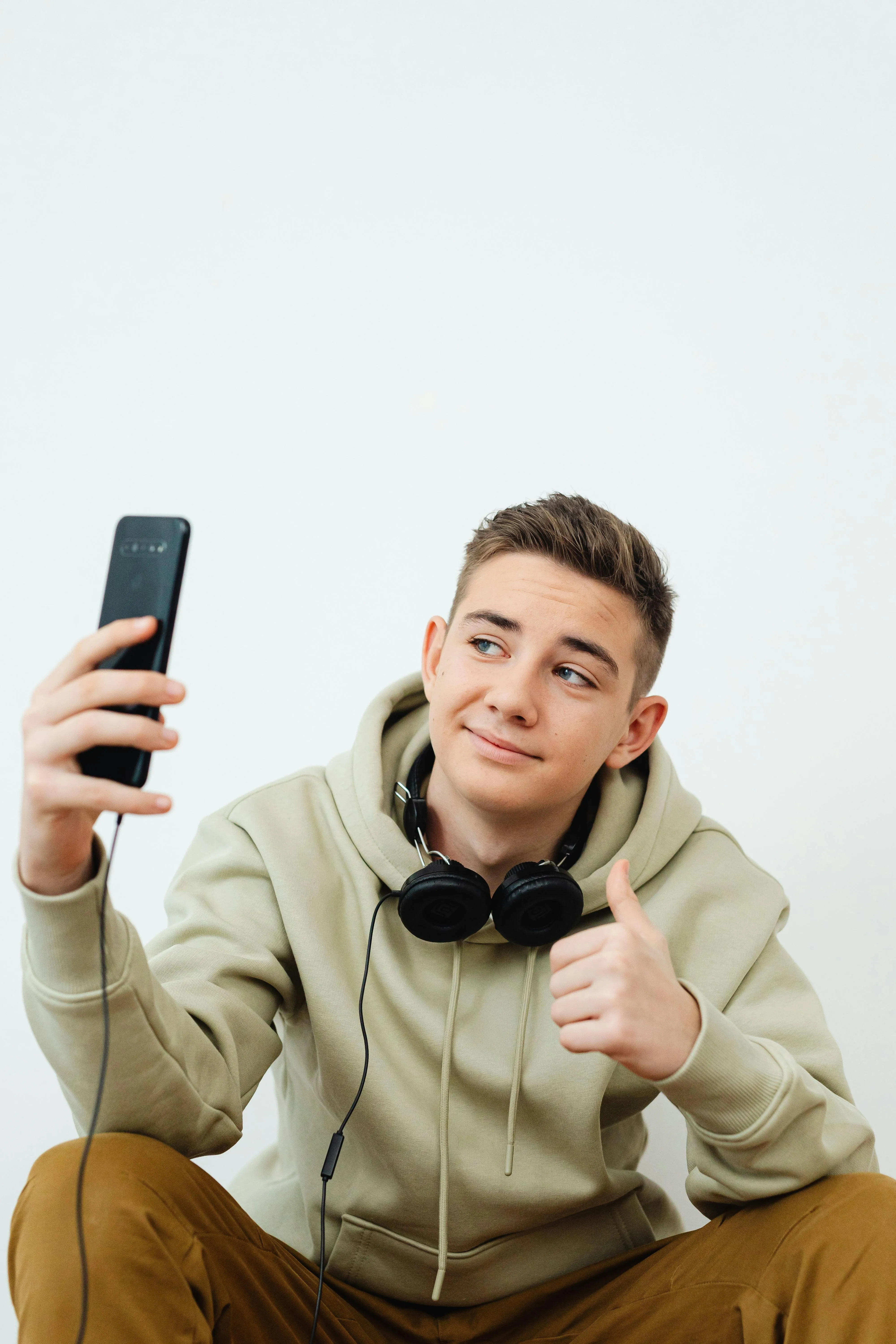 Парень делает селфи на смартфон и показывает жест одобрения